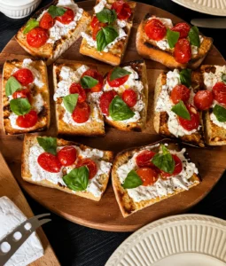 Bruschetta met burrata en geroosterde tomaatjes, afgemaakt met basilicum en olijfolie