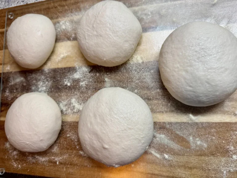 Opgebolde bollen pizzadeeg in een deegbak, klaar voor de koude rijs in de koelkast