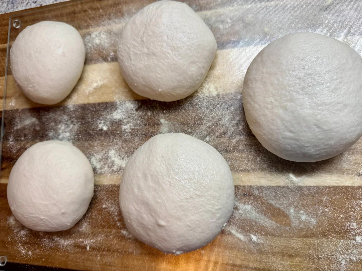 Opgebolde bollen pizzadeeg in een deegbak, klaar voor de koude rijs in de koelkast